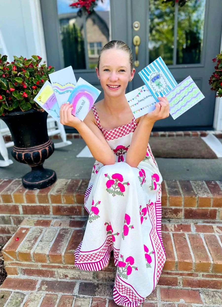 Viv smiling and holding several of her own colorful hand-drawn cards